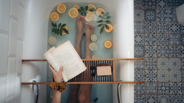 woman reading a book in a baththub filled with slices of orange